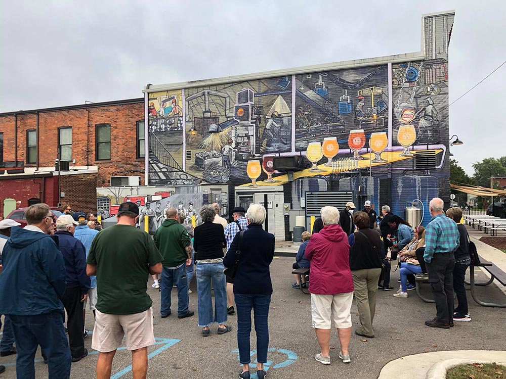 A crowd gathers to see the dedication of the mural on the back of the Malleable Brewery