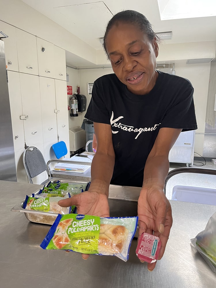 LaShawn Davis shows a sample of a Meet Up and Eat Up summer lunch that includes a cheesy pull-apart sandwich, fruit, vegetables, and milk. Meals are prepared by Marshall Public Schools and offered to all children and teens under 18, with no registration required.